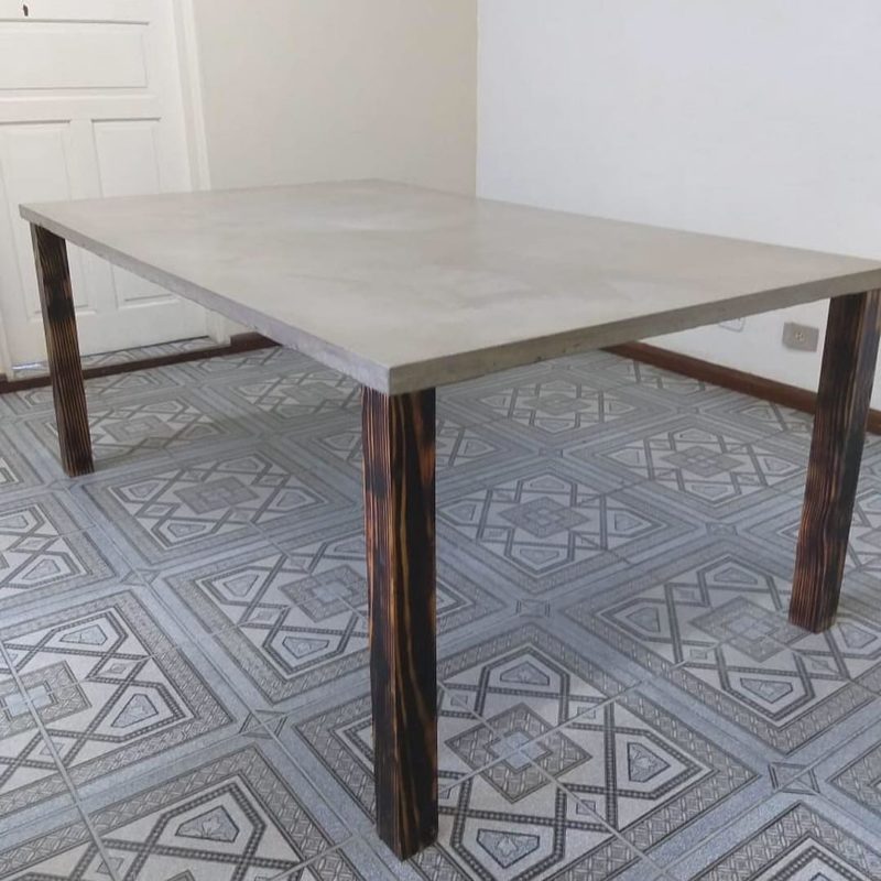 Mesa com tampo de concreto e pés de madeira.
